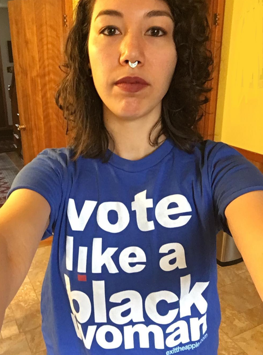 image of a light-skinned woman of color with shoulder length curly hair looking straight into the camera. text on her shirt reads 'vote like a black woman'