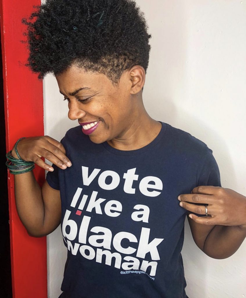 image of a smiling black woman with short hair looking to the left. text on her shirt reads 'vote like a black woman'